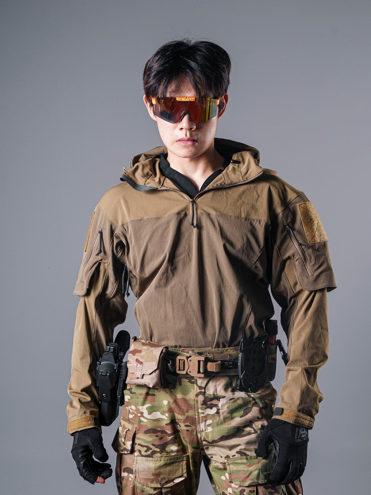 Front view of a model wearing the tan Gryphon Crocodile Halfshell Jacket with its high collar and a tactical belt.