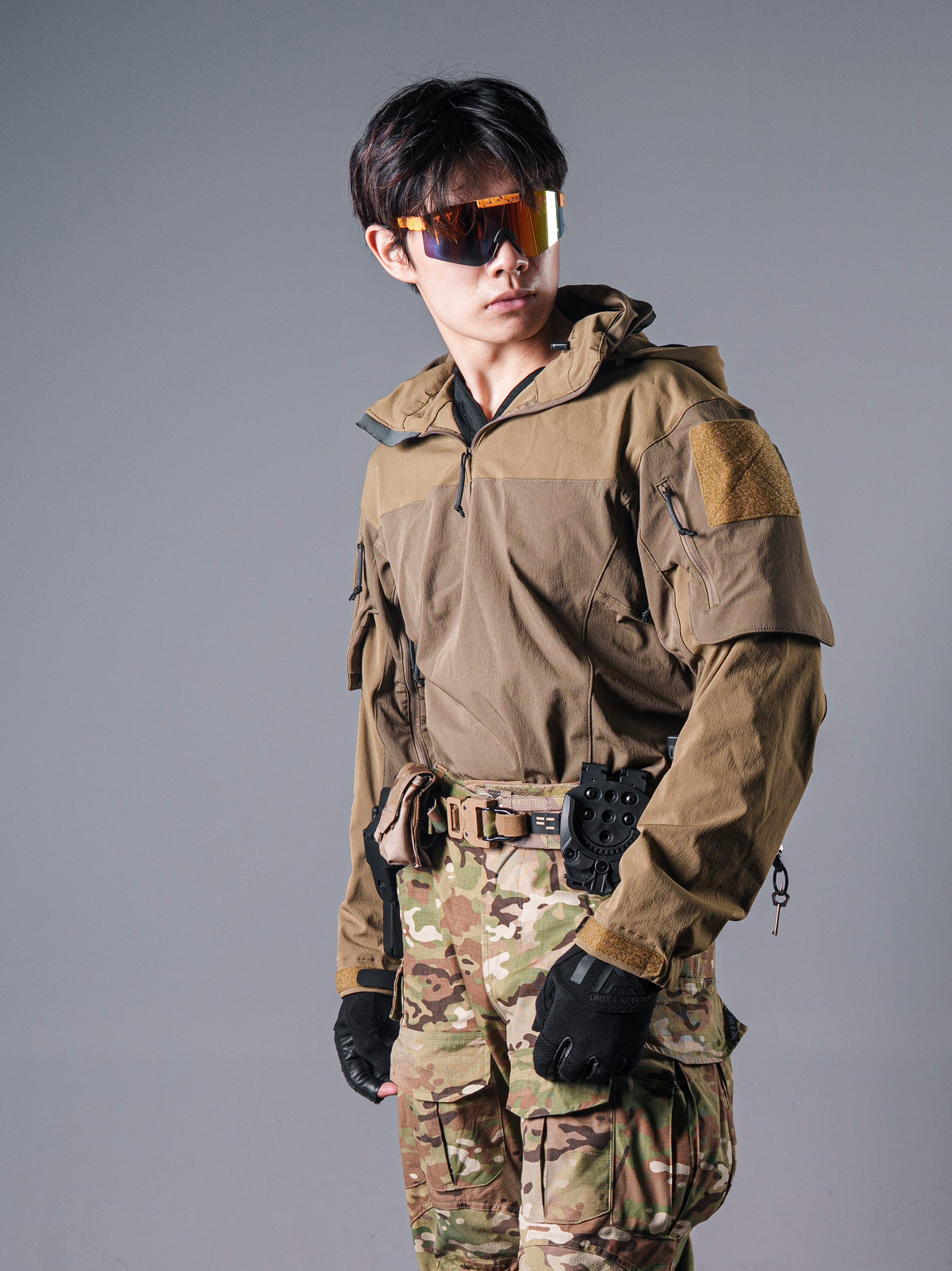 Front view of a model wearing the tan BKG ARC-style Gryphon Crocodile Halfshell Jacket with a hood and sleeve patches.