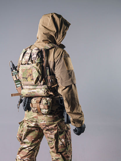 Rear view of a model wearing the tan BKG ARC-style Gryphon Crocodile Halfshell Jacket with the hood up and tactical gear.