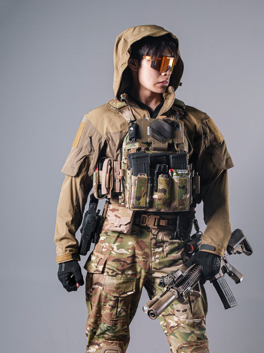 Model wearing the tan BKG ARC-style Gryphon Crocodile Halfshell Jacket with the hood up beneath a tactical chest rig.