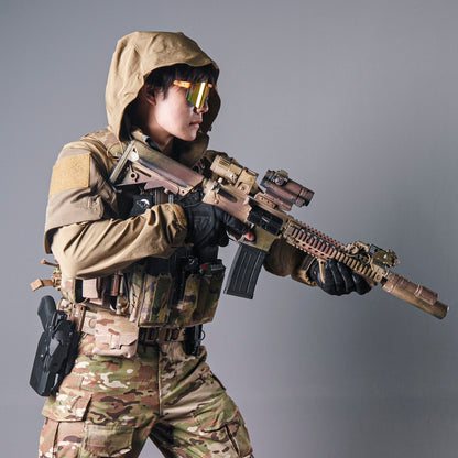 Model wearing a tan BKG ARC-style Gryphon Crocodile Halfshell Jacket with the hood up while holding a rifle.