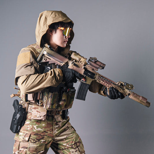 Model wearing a tan BKG ARC-style Gryphon Crocodile Halfshell Jacket with the hood up while holding a rifle.
