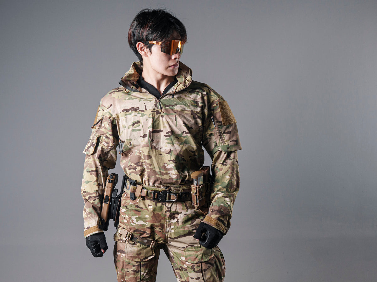 Front view of a model wearing the Multicam Gryphon Halfshell Jacket zipped with matching camouflage trousers and a tactical belt.