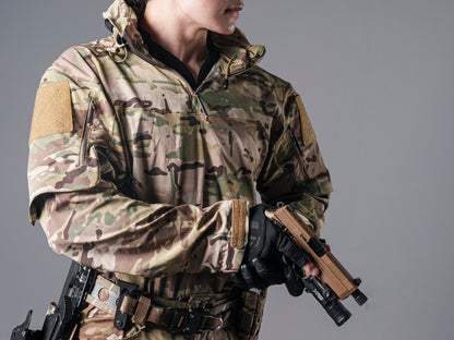 Close-up of a model wearing the Multicam Gryphon Halfshell Jacket and holding a tan handgun with a mounted light.