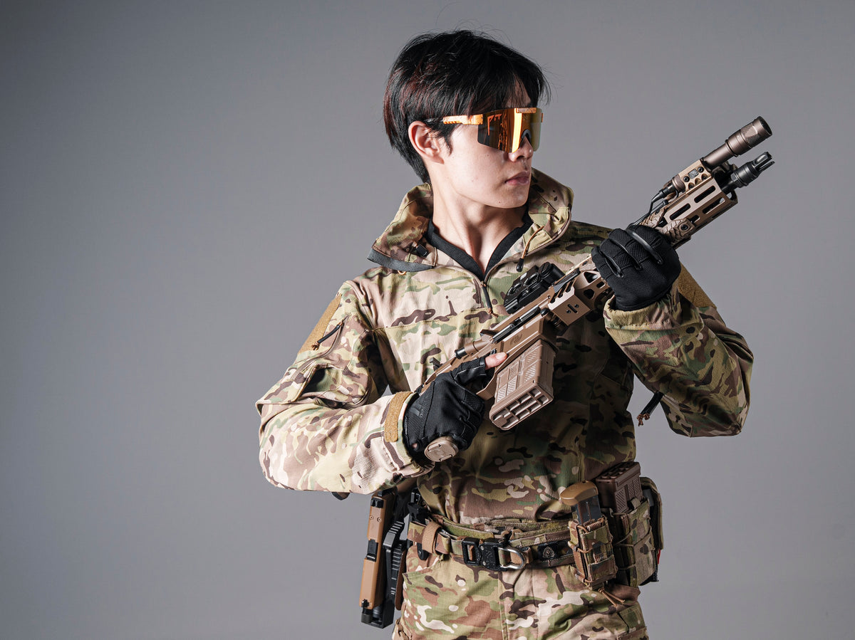 Model wearing the BKG ARC-style Gryphon Multicam Halfshell Jacket and holding a rifle across the chest.