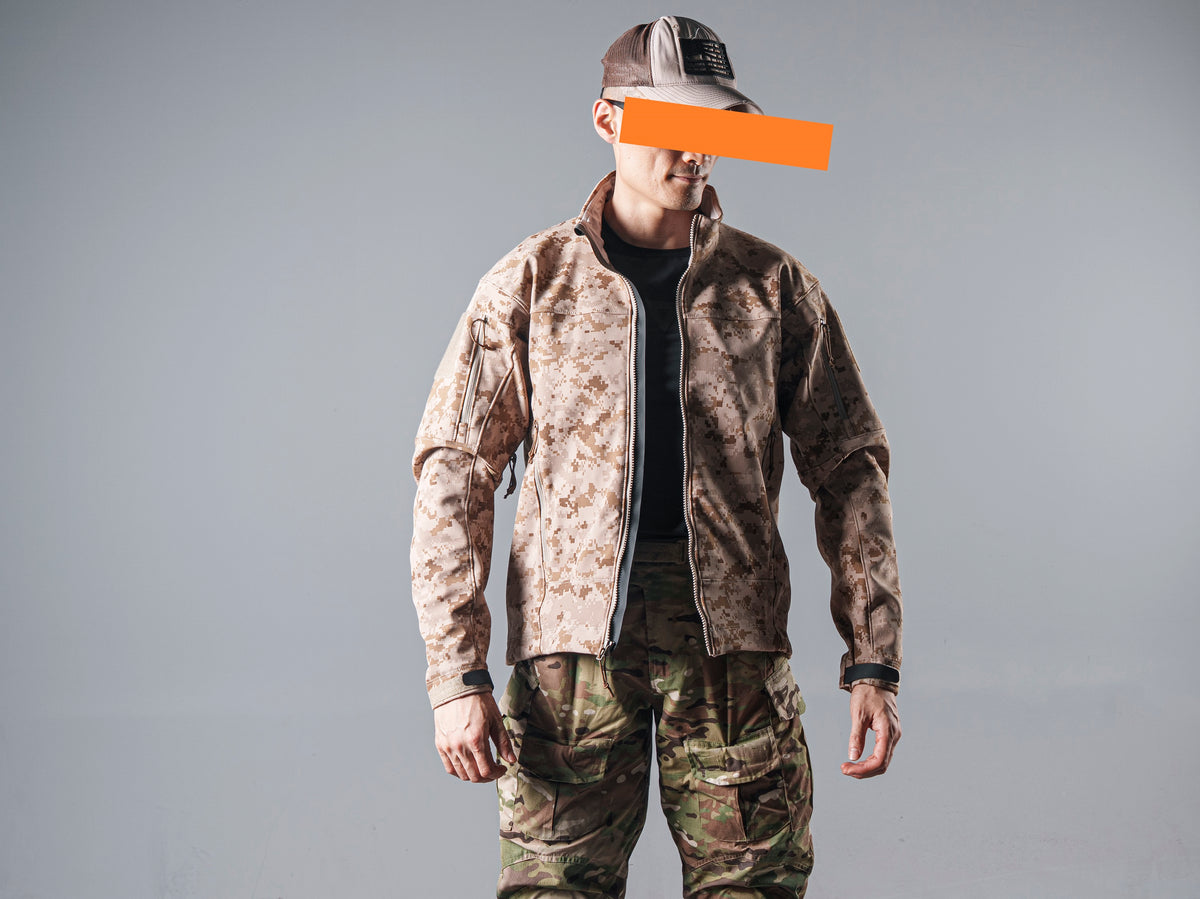 Front view of a model wearing the zipped tan AOR1 digital camouflage Minotaur softshell jacket with matching camouflage pants.