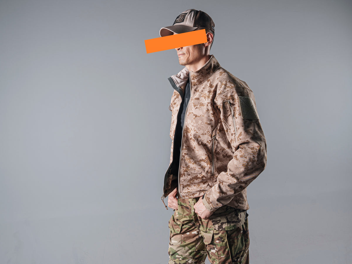 Side view of a model wearing the tan AOR1 digital camouflage BKG ARC-Style LEAF Minotaur softshell jacket zipped to the collar.