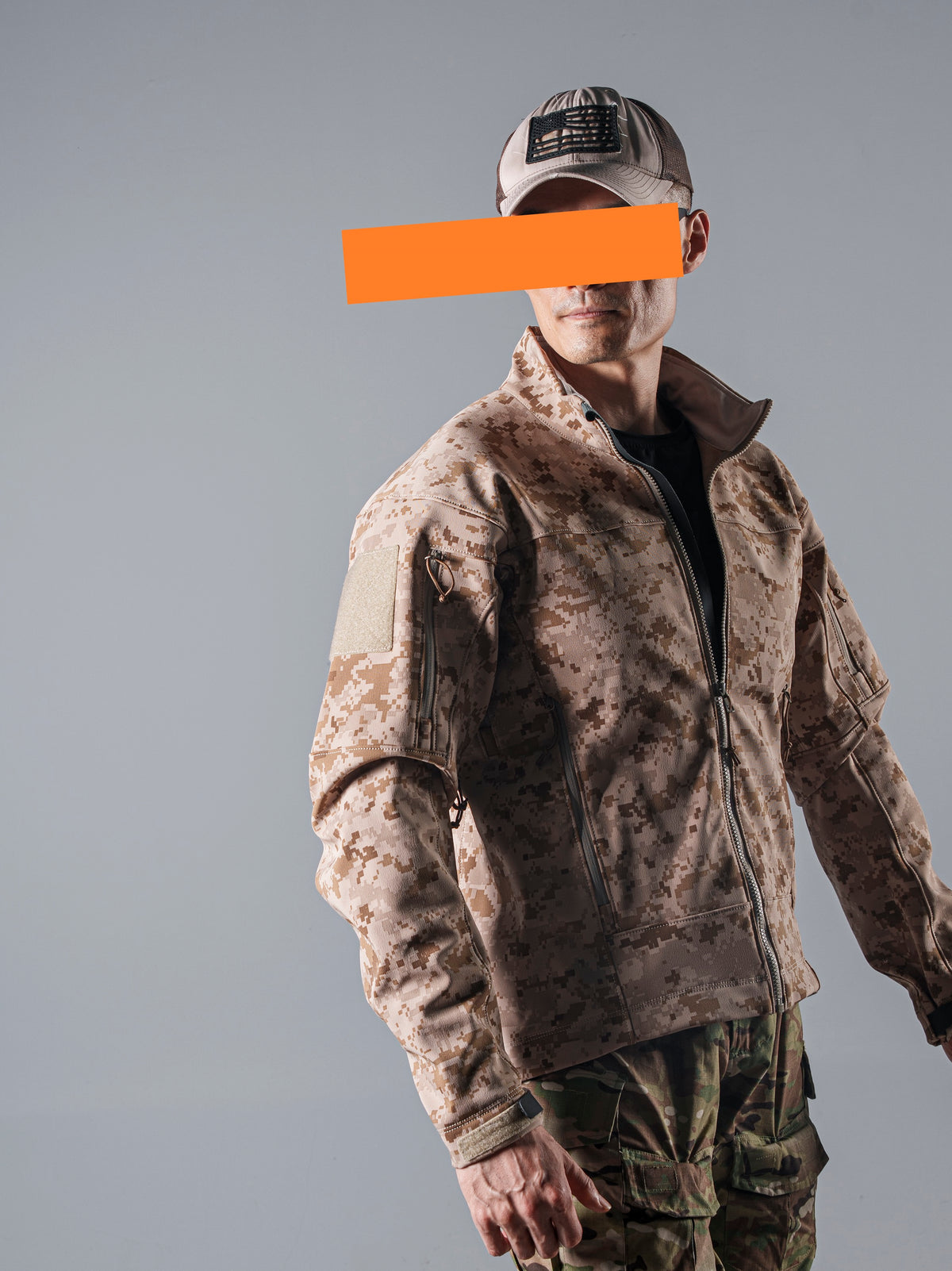 Three-quarter studio view of a model wearing the tan AOR1 digital camouflage Minotaur softshell jacket zipped to the collar.