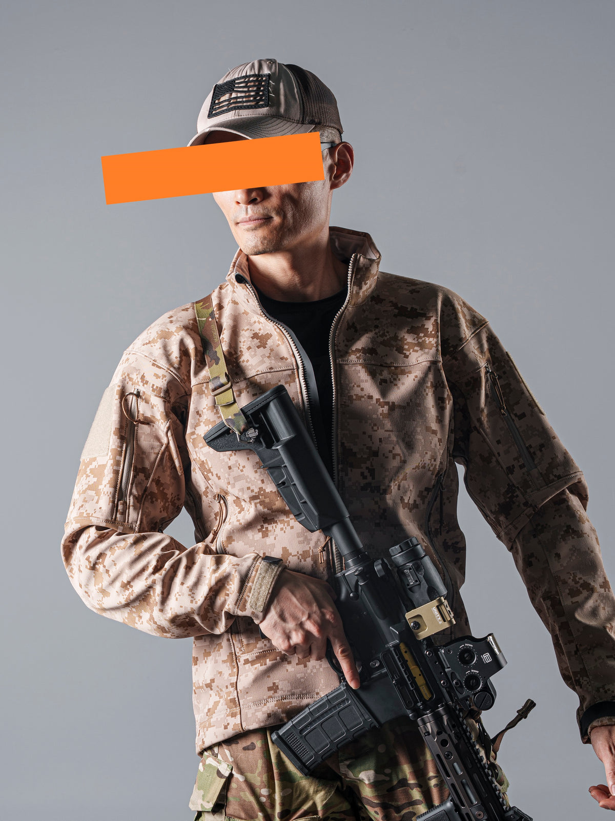 Model wearing the tan AOR1 digital camouflage BKG ARC-Style LEAF Minotaur full-zip softshell jacket while holding a rifle.