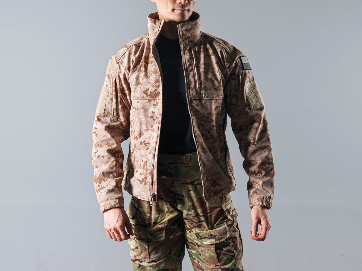 Close front view of the tan AOR1 Cold Fusion jacket open over a black shirt, showing its zipper, chest panels and sleeve patch.