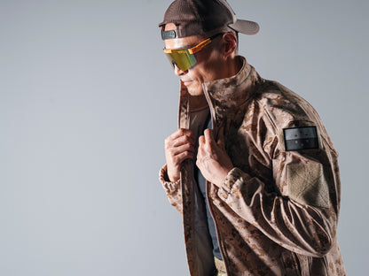 Close side view of the tan AOR1 Cold Fusion jacket as a model adjusts its raised collar.