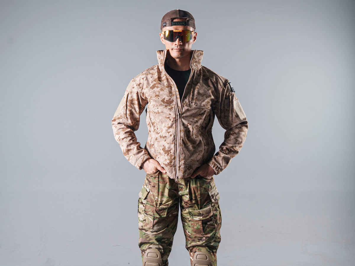 Front view of a model wearing the zipped tan AOR1 Cold Fusion softshell jacket with a black shirt and camouflage trousers.