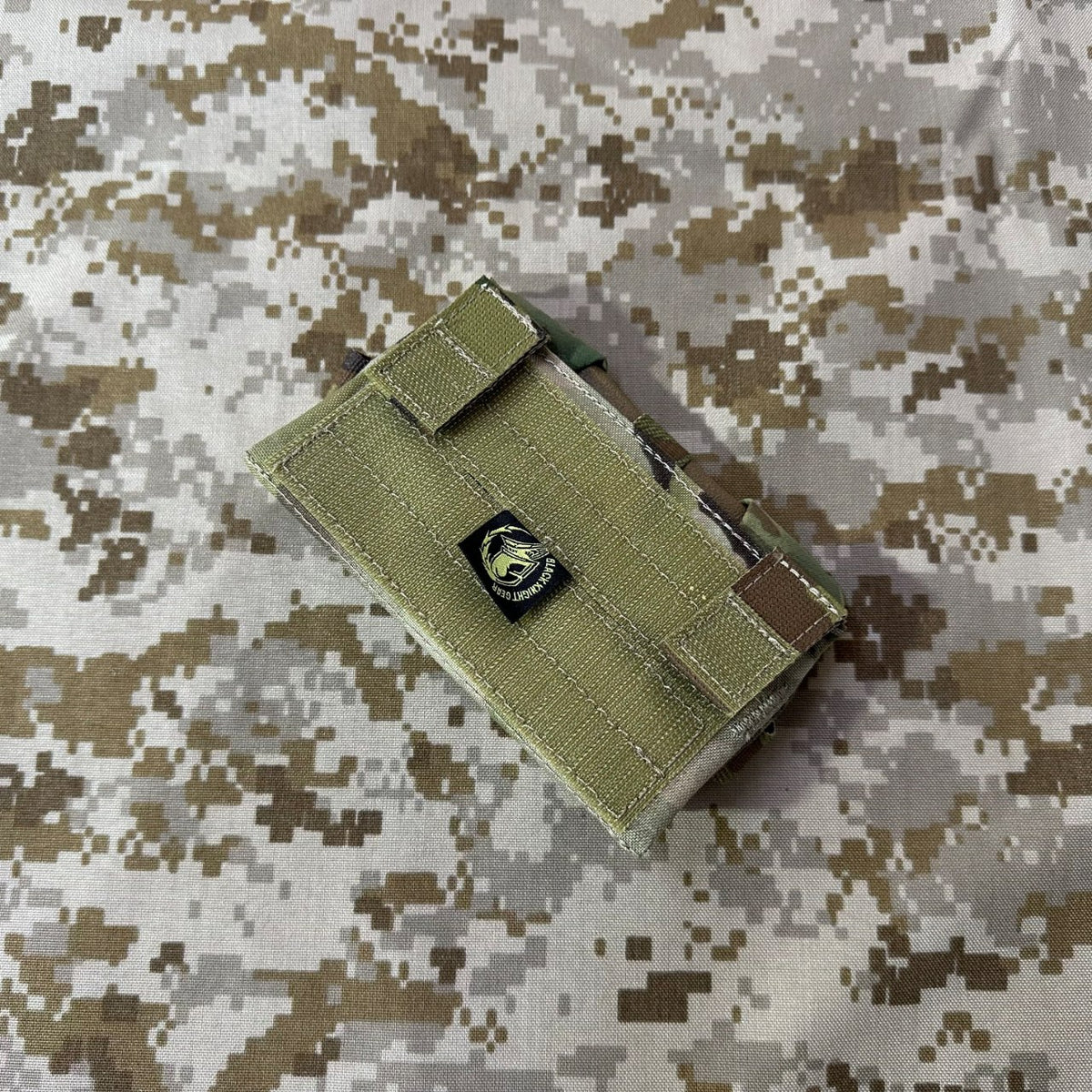 Front of the olive Garmin M650 GPS flip pouch showing its hook-and-loop closure strap and branded patch.