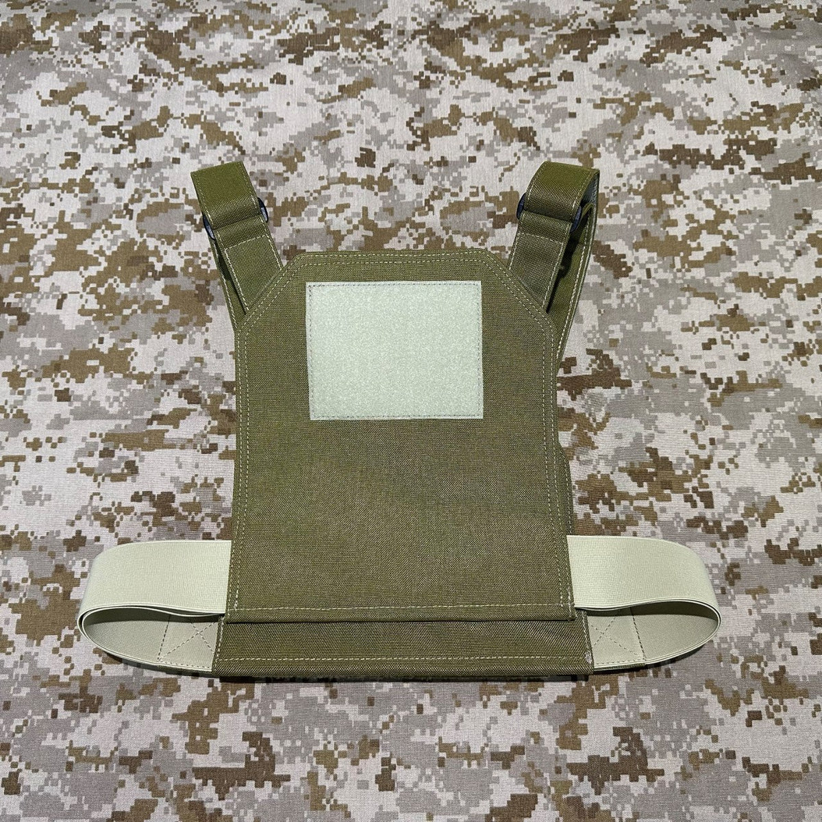 Back view of the olive plate carrier showing a square hook-and-loop panel, shoulder straps and adjustable side cummerbund.