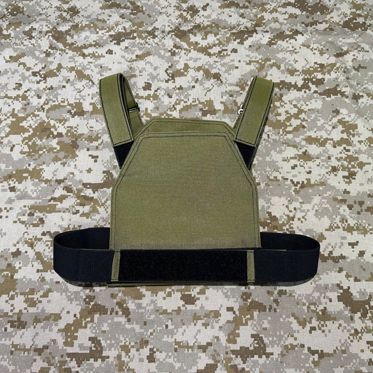 Rear view of the olive low-vis plate carrier with a black waist band on AOR1 digital camouflage fabric.
