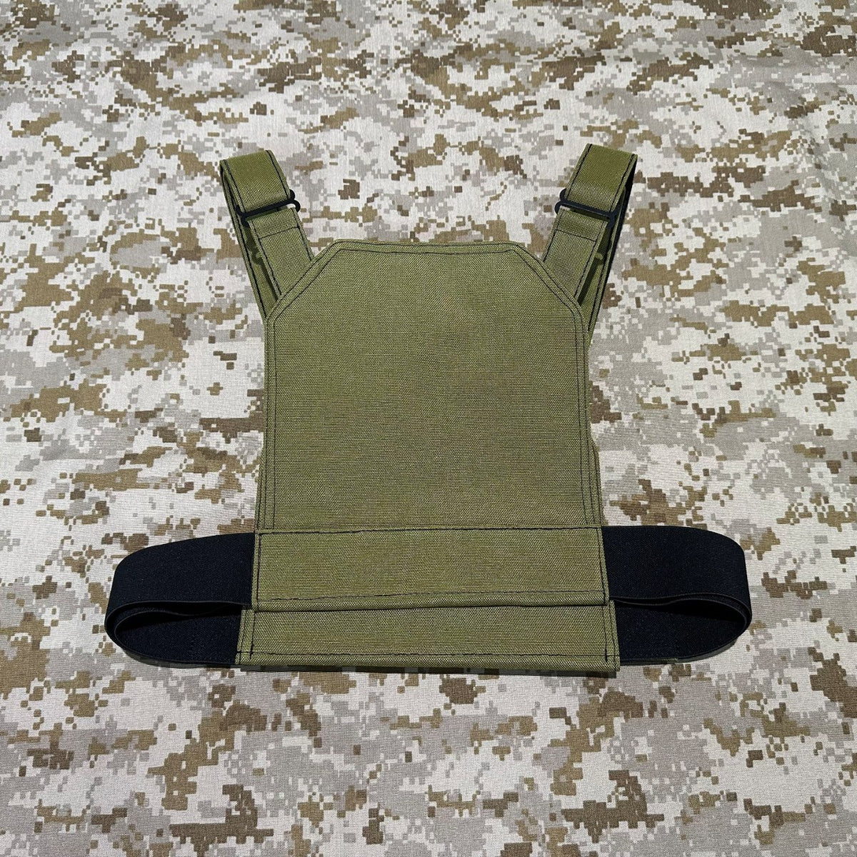 Rear view of the olive BKG DB-Style Low-Vis Chicken Plate Carrier showing adjustable shoulder straps and a black waist band on camouflage fabric.